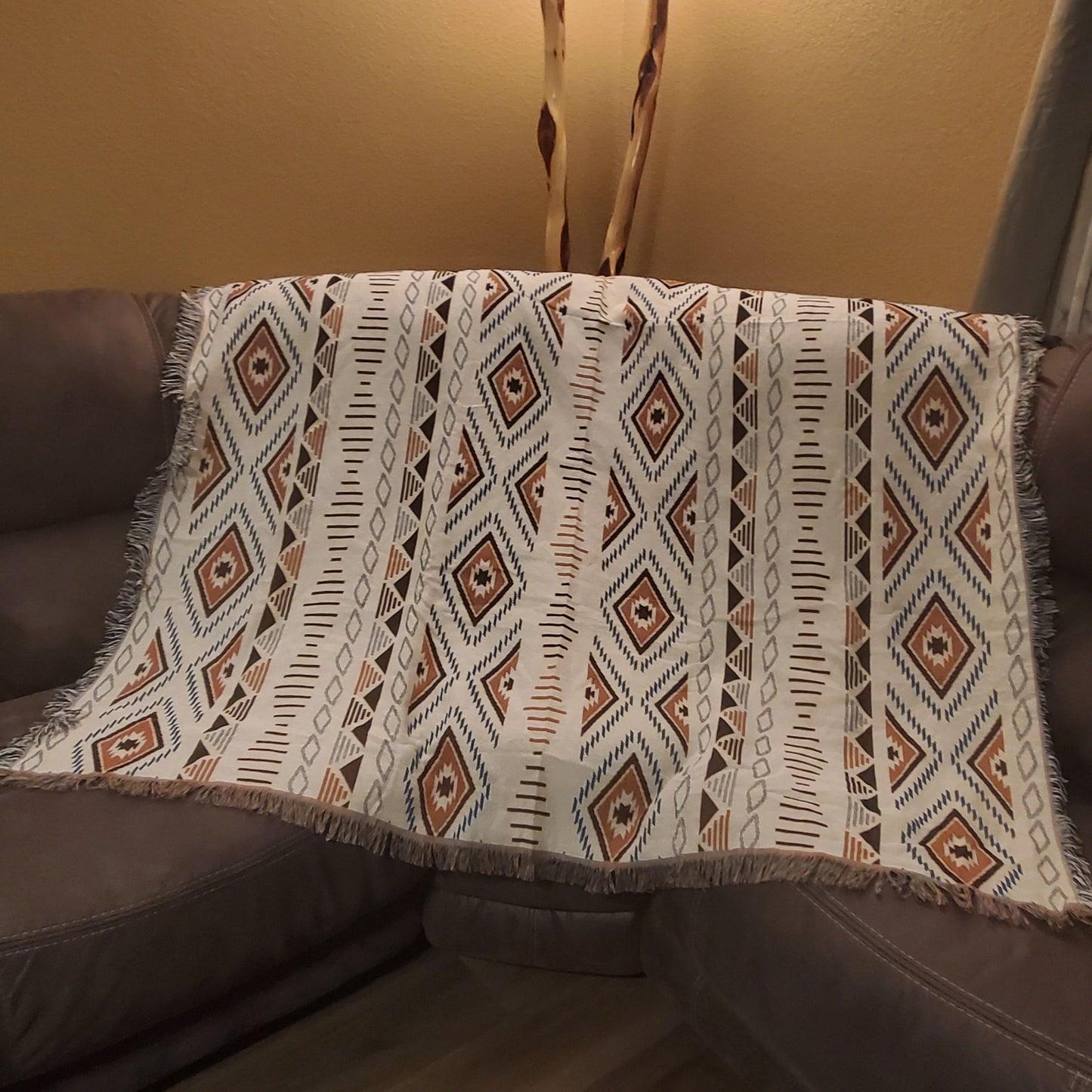 A sofa blanket with a geometric Aztec pattern in white, black, and brown colors