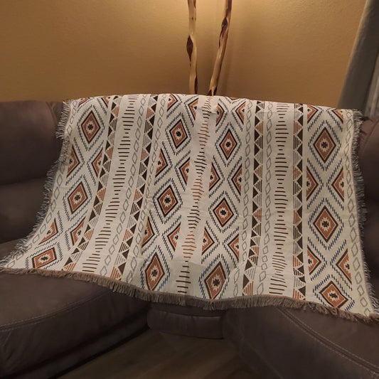 A sofa blanket with a geometric Aztec pattern in white, black, and brown colors 
