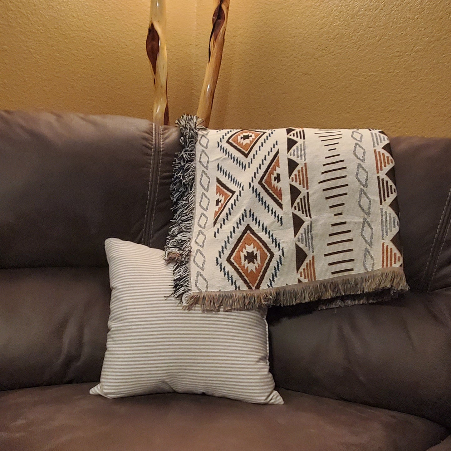 A sofa blanket with a geometric Aztec pattern in white, brown & black colors