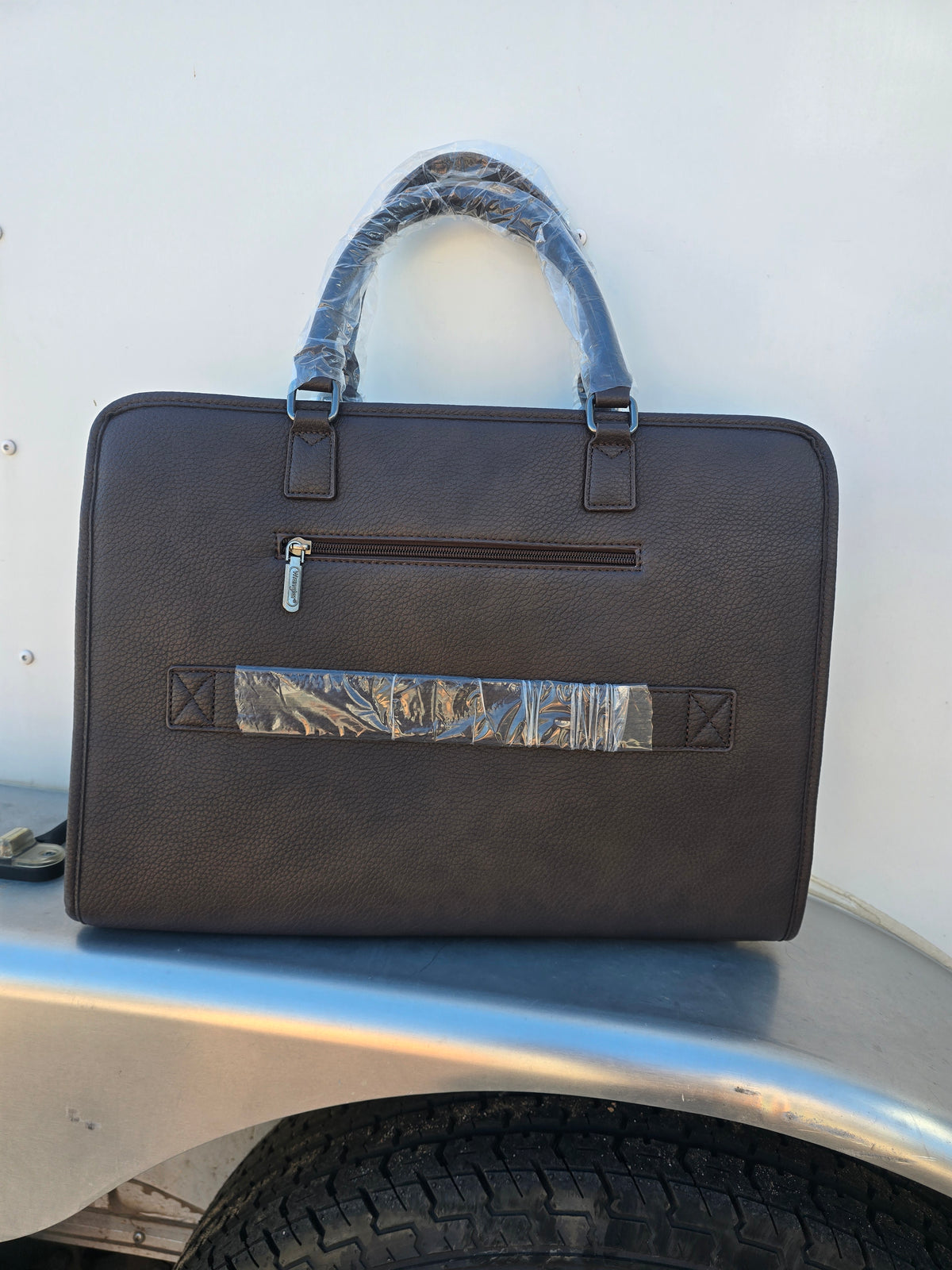 Back of Brown Wrangler PU Leather Laptop bag with exterior pockets, luggage strap, interior pockets, shoulder strap and carrying handle