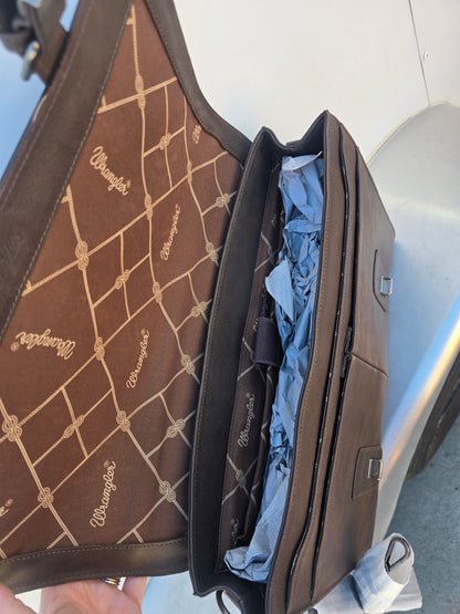 A brown leather briefcase or satchel shown open, with the interior lining visible. The exterior and lining feature a repeating tan geometric lattice pattern with the brand name 'Wrangler' printed in script.